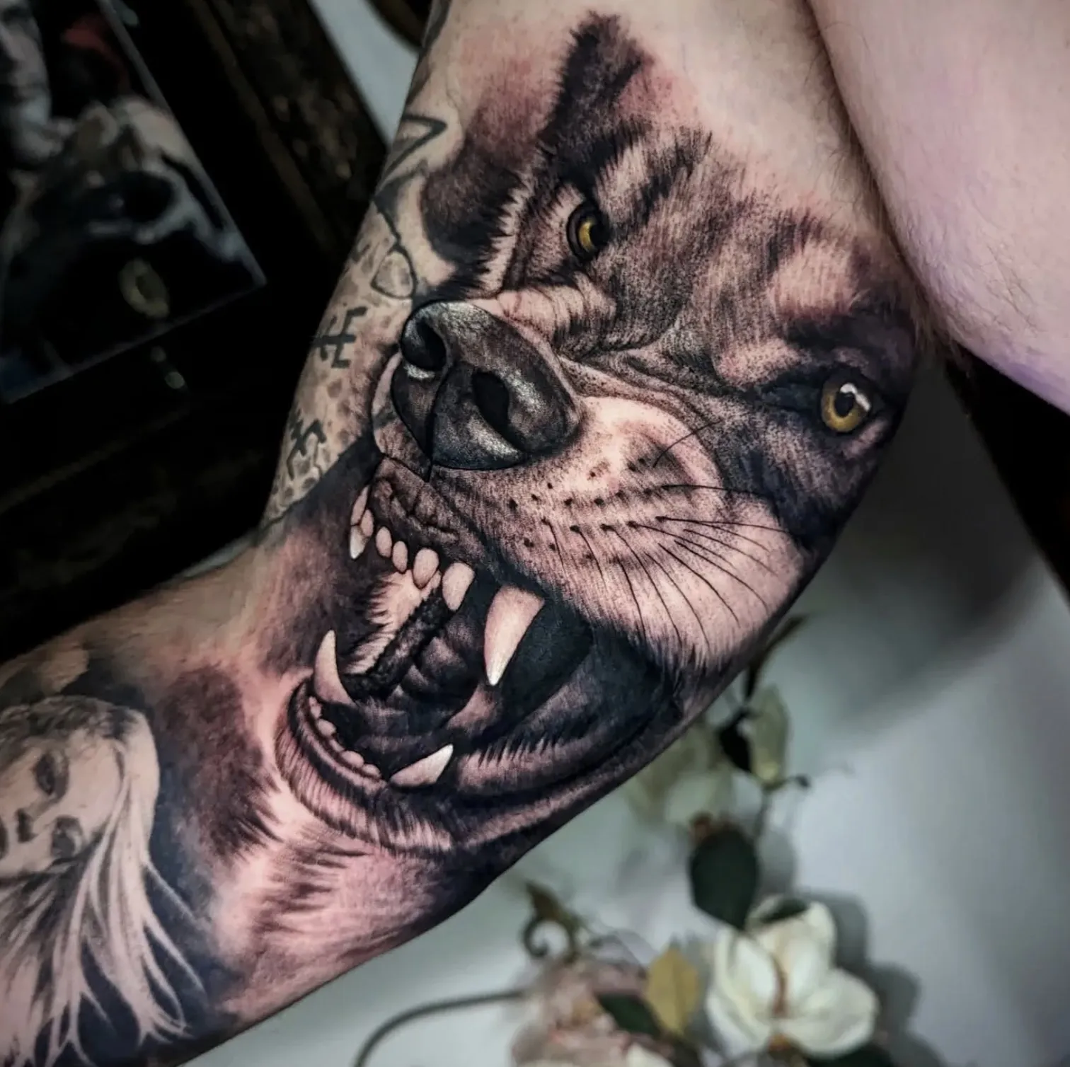 Black and grey wolf portrait tattoo with intense eyes and detailed fur
